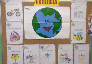 Na tablicy plakat związany z Dniem Ekologa. Pośrodku zdjęcie planety Ziemia, wokół pokolorowane przez dzieci ilustracje z napisami.