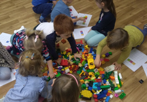 Dzieci tworzą konstrukcje z klocków Lego.