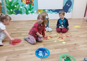 Dzieci segregują figury geometryczne ze względu na kolor.
