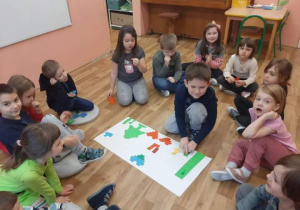 Dzieci siedzą w kole i wykonują zadanie z kodowania