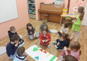 Dzieci siedzą w kole i wykonują zadanie z kodowania