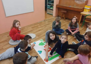 Dzieci siedzą w kole i wykonują zadanie z kodowania
