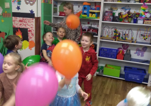 Dzieci tańczą z kolorowymi balonami.