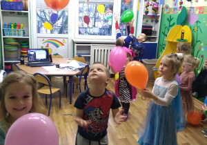 Dzieci tańczą z kolorowymi balonami.