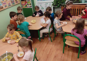 Przedszkolaki z grupy 3 siedzą przy stolikach. Dzieci jedzą wykonana przez siebie sałatkę owocową.