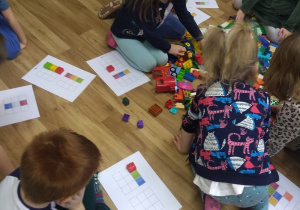 Dzieci odzwierciedlają klockami Lego wzór podany na kartce . Zabawa w kodowanie