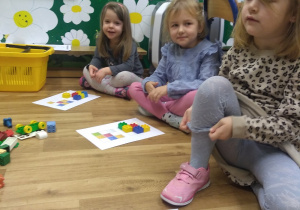 Dzieci siedzą w kole. Odzwierciedlają klockami Lego wzór podany na kartce . Zabawa w kodowanie