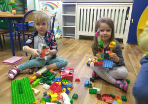 Zosia i Monika prezentują wykonane przez siebie konstrukcje z klocków Lego.