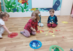 Dzieci segregują figury geometryczne ze względu na kolor.