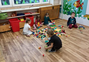 Dzieci tworzą konstrukcje z klocków Lego.