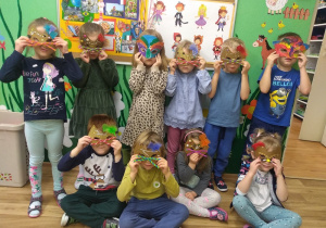 Dzieci pozują w wykonanych przez siebie maskach karnawałowych.