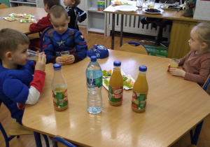 Dzieci piją soki, wodę oraz jedzą owoce.