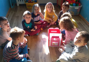 Dzieci z grupy 2siedza wokół skrzynki wypełnionej kartkami walentynkowymi.